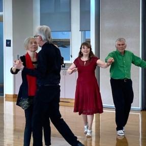 Older adult couples practice steps in a tango dance class.